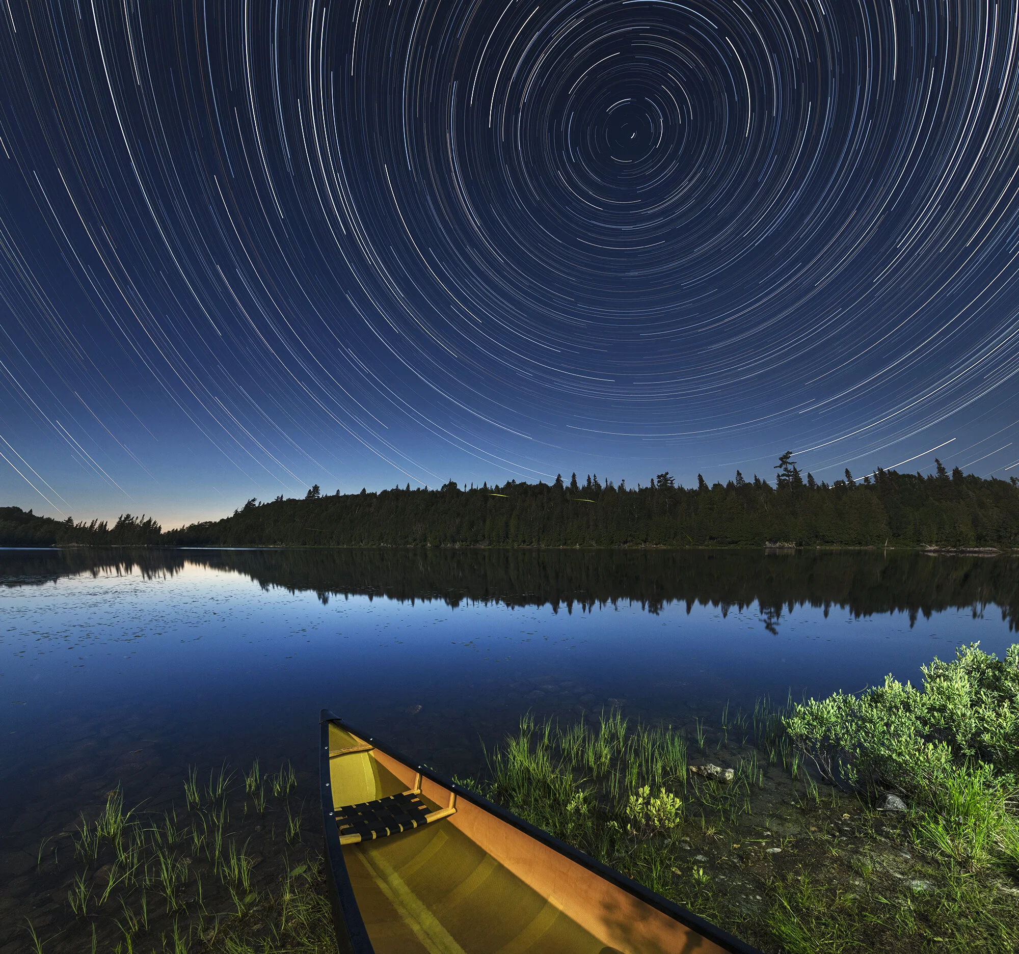 Canoe on water with star trails